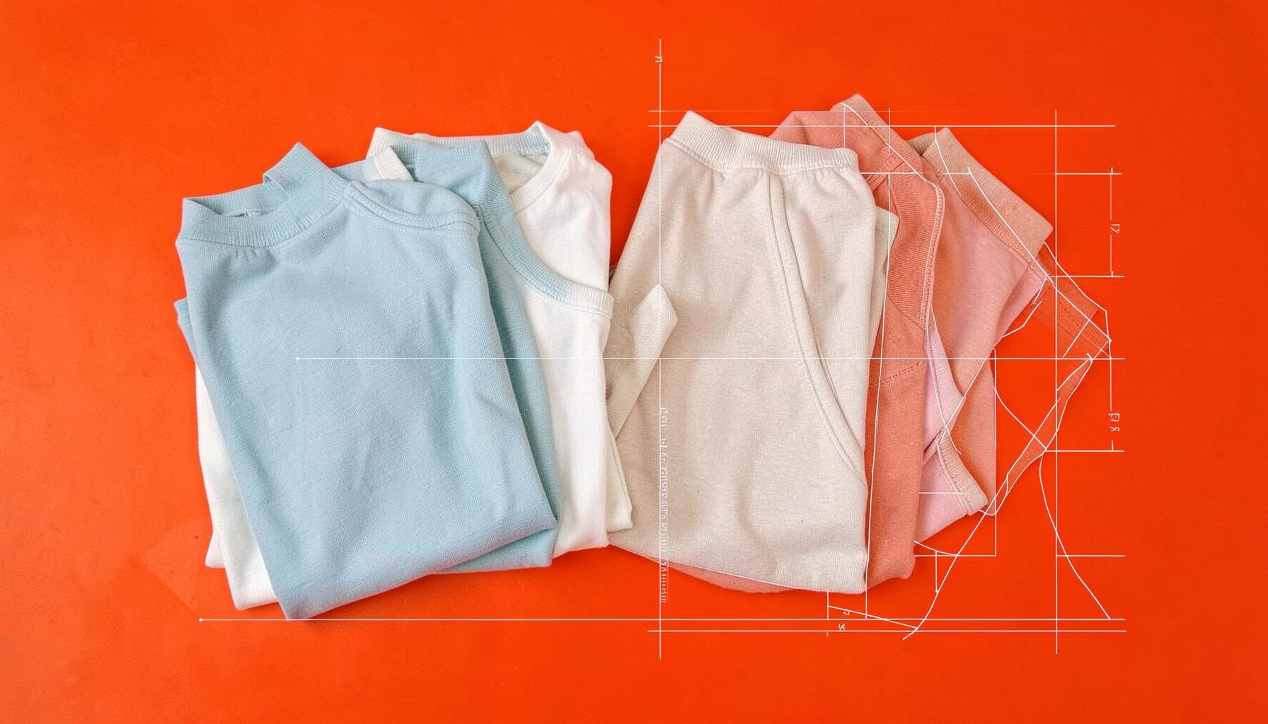 Flat lay of folded women's clothing in soft neutral and ocean-blue tones on a light textured surface